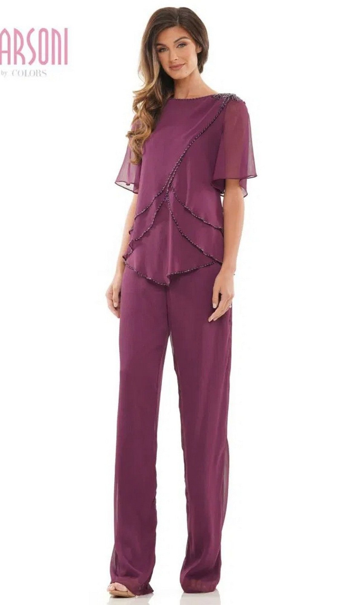 A woman wearing the eggplant Marsoni M321 long formal pantsuit with short sheer sleeves and beaded edges stands facing forward against a white background.